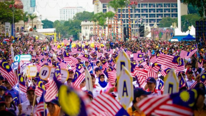 A Crowd of Maylasians Holding the Malaysian Flag marching in the street